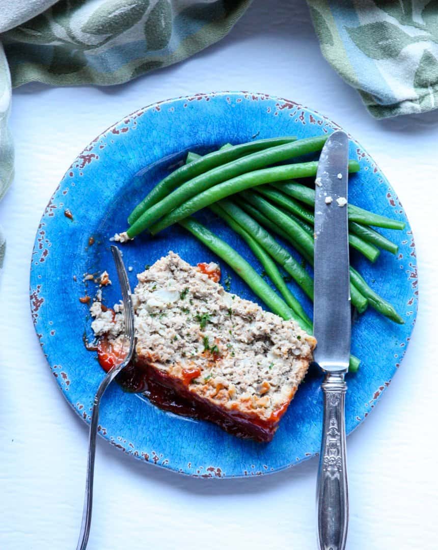 A piece of meatloaf  on a plate with a fork and knife