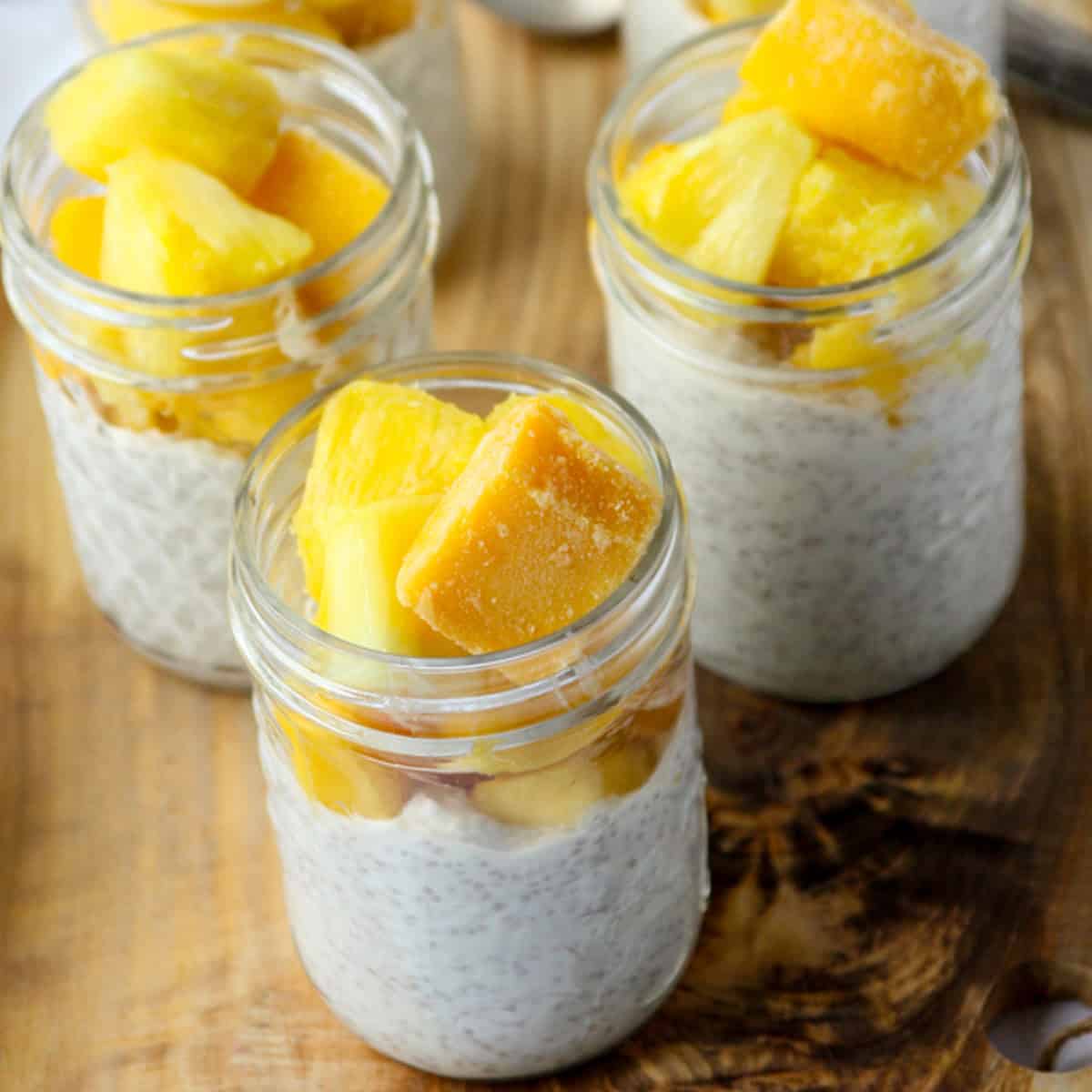 Three jars of chia pudding topped with mango.