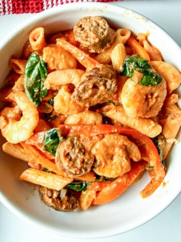 Cajun shrimp & sausage pasta in a white bowl.