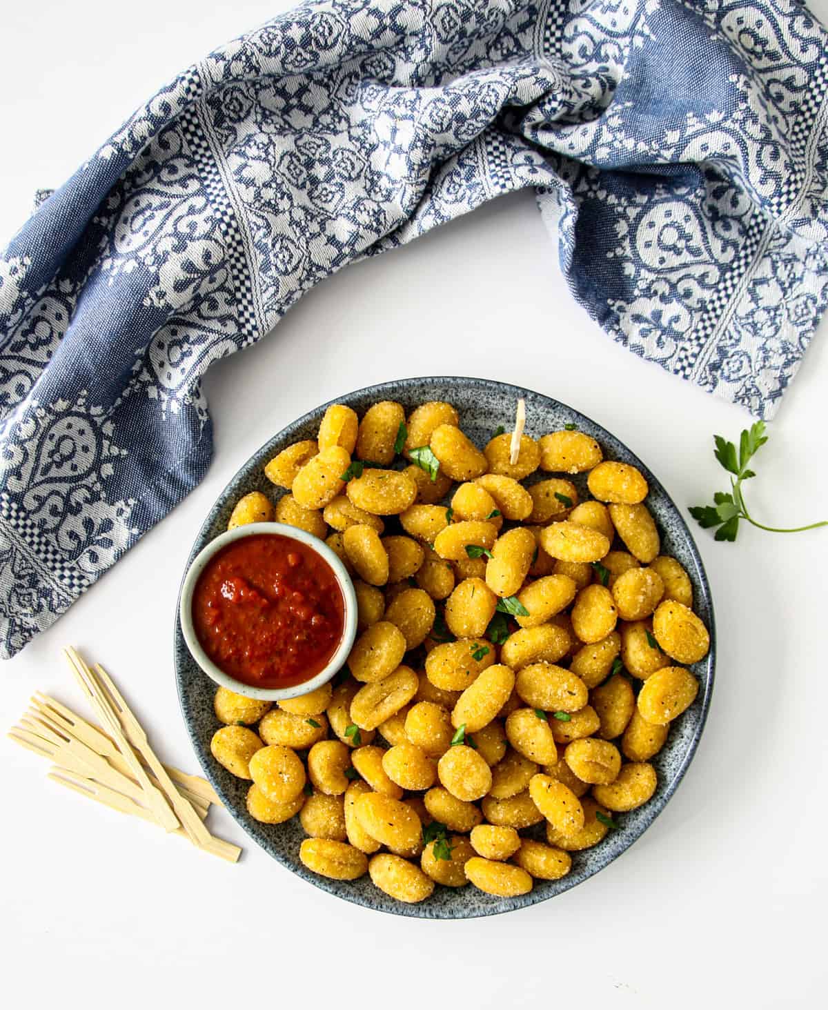 A plateful of air fryer gnocchi with a small dish of tomato sauce.